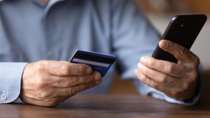 senior man holding phone and credit card